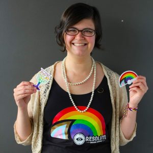 Woman wearing a rainbow shirt with a rainbow sticker in each hand