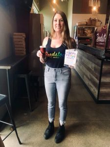 A person holds a beer while wearing a shirt with Seedstock with rainbow gradiant